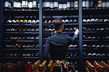 Sommelier Bartender Man At Wine Shop Full Of Bottles With Alcohol Drinks, Back View