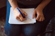 © Robert Petrovic - Close up shot of female's hand writing down a message on the notepad in her lap
