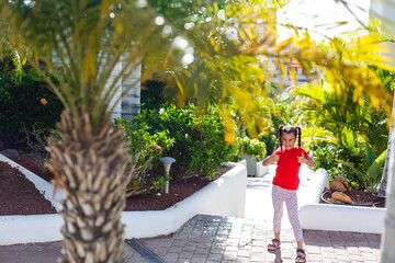 Wall Mural - The concept of family happiness and children in the summer on the sea among palm trees. Cute little girl without a pattern.