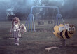 Creepy, foggy playground with a little girl holding a teddy bear