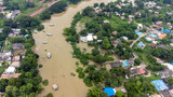Fototapeta  - Flood waters overtake a house and rice field at Central of Thailand in 2021. Many buildings are submerged in water. Photo disaster from above view by drone