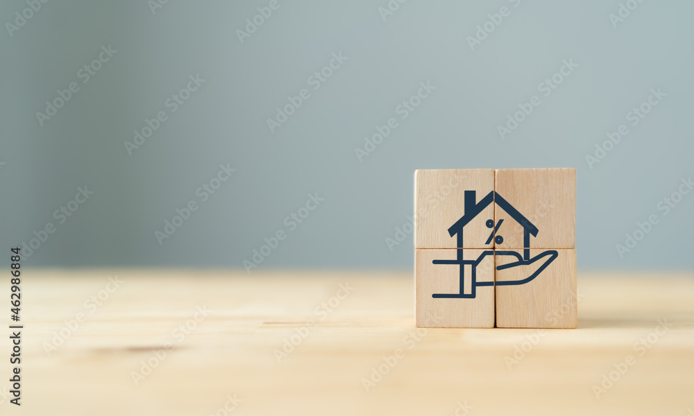 Home loan, mortgage and buy a real estate concept. The wooden cube with icon of hands holding house model in grey background and copy space. Banner for home buying, loan and insurance