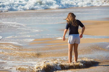 Wall Mural - cute little girl playing with foam by the sea