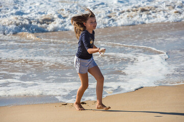 Wall Mural - cute little girl playing with foam by the sea