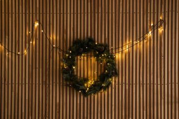 Wall Mural - Aesthetic Scandinavian hygge home interior: warm glowing garland lights, Christmas wreath hanging on wooden rails wall. Christmas, New Year holidays decor