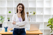 © kamiphotos - Portrait of a young beautiful Asian woman standing in a white office room, concept image of Asian business woman, modern female executive, startup business woman, business leader woman.