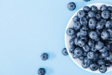 Fresh berries blueberry on blue background. Colorful fruit pattern of blueberries as background. Creative berries concept. Flat lay, top view, copy space