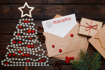 Wall Mural - Christmas tree made of beads and Letter in an envelope with the inscription merry christmas on wooden background with fir branches