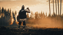 Medieval Knight Looking At Sunrise. Romantic Hero, Soldier, Warrior In Body Armour With Sword On A Journey To Safe Princess. Mysterious Smoke, Magic Forest And Adventure. Back View Shot