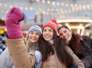 Poster - friendship, technology and winter holidays concept - happy smiling teenage girls taking selfie with smartphone over christmas market or amusement park background