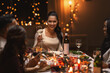 © Syda Productions - holidays, party and celebration concept - multiethnic group of happy friends having christmas dinner at home and drinking wine