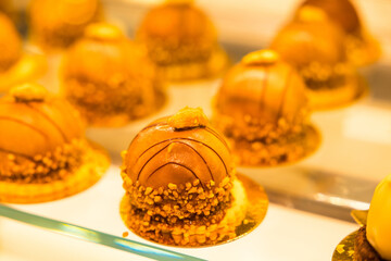 Canvas Print - Close-up shot of delicious desserts covered with caramel and nuts on the glass shelf at a bakery