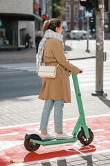 traffic, city transport and people concept - woman riding electric scooter along red bike lane with signs of bicycles and two way arrows on street