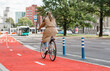 © Syda Productions - traffic, city transport and people concept - woman riding bicycle along red bike lane or two way road on street