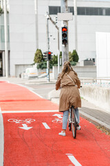 Wall Mural - city transport and people concept - woman with bicycle waiting for green traffic light signal on red bike lane in tallinn, estonia