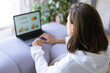 © Анастасия Каргаполов - Young woman at home on sofa in a white hoodie with a laptop, advisor financial business analytics woman with data dashboard graphs