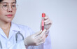 © Prapat - Focus on female doctor's hand in medical gloves holding test tube with red blood for testing in white laboratory room, medical and science concept