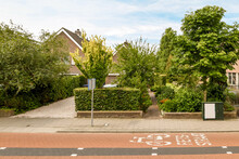 Bicycle Road Against Houses And Pavement With Shrubs In Town