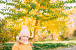 © Анна Молько - girl in a yellow jacket and hat on a background of autumn trees. autumn in the city. joyful time of year.