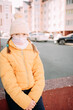 © Анна Молько - sad girl in a yellow jacket and medical mask sits on a concrete slab on the background of the autumn city.