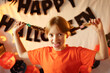 © Анна Молько - girl with pigtails having fun on a background of Halloween attributes. knitted orange pumpkins. preparation for the holiday. garlands on the walls.