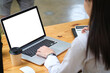 © saltdium - Behind view of a young accountant working with a white screen computer laptop and calculator at the wooden table surrounded by a coffee cup and various equipment.