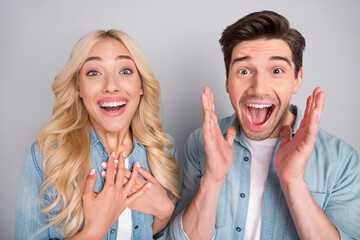 Poster - Photo of impressed adorable young people wear denim shirts rising arms hands chest smiling isolated grey color background