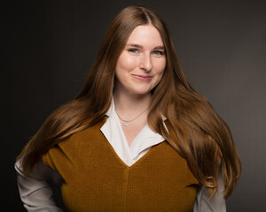 Young woman with long hair poses before a dark grey background in a Downtown Los Angeles Studio