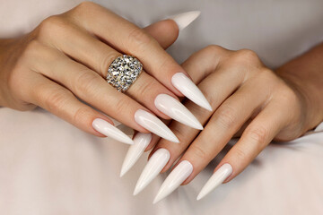 Long light manicure with jewelry on a woman's hand.