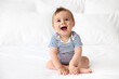 © Lisa Tichané - Cute laughing baby sitting on white bed