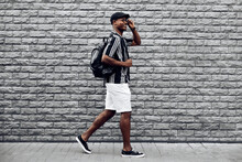 African American Man In A Summer Shirt And Shorts, Steps Against A Black Brick Wall, Black Guy