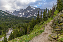 Grinnell Glacier Trail - A Stormy Spring Evening View Of Cliffside Grinnell Glacier Trail, With Mt. Gould Towering In Background And Grinnell Creek Running Below. Many Glacier, Glacier National Park.
