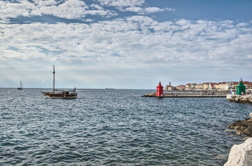 Wall Mural - View of the red and green lighthouses on a pier,  boat and the architecture of  the city on the horizon, Piran, Slovenia.