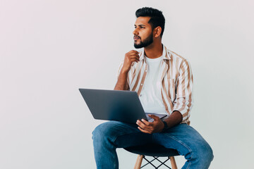 Portrait of business Indian man using laptop computer, looking side and smiling, standing on white background