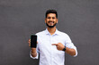 © F8  \ Suport Ukraine - Portrait of cheerful, positive, attractive man having smart phone with black screen in hand, pointing with forefinger to product, isolated on grey background