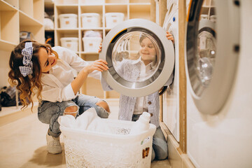 Mother with daughter doing laundry at self serviece laundrette