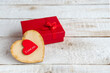 Red gift box and a heart with the text I love you on a white wooden background.