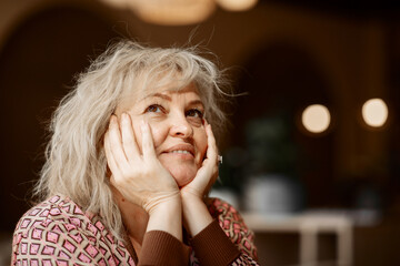 Portrait of an attractive adult blonde of European appearance sitting thoughtfully at a table in a cafe close-up