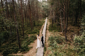 Canvas Print - Top view of a beautiful Caucasian (white) bride and groom in a forest in Lithuania