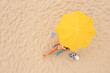 © New Africa - Woman resting in sunbed under yellow beach umbrella at sandy coast, aerial view. Space for text