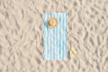 Striped Beach Towel, Straw Hat And Flip Flops On Sand, Aerial View