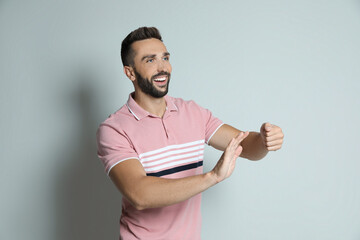 Wall Mural - Happy man pretending to drive car on grey background