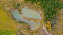 Little Lake Or Pond Of Unusual Shape With A Beautiful Autumn Nature Photographed From Above With A Drone. Real Is Beautiful 