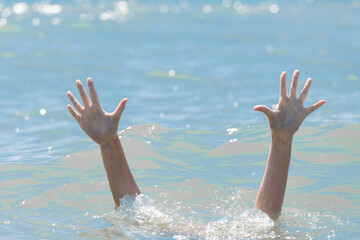 A hands from under the water of a drowning girl, help and urgent rescue of a person during a dangerous swimming, sos