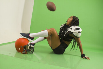 sitting woman with braids american football ball and shoulder pads