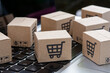 © Achira22 - Online shopping - Paper cartons or parcel with a shopping cart logo on a laptop keyboard. Shopping service on The online web and offers home delivery..