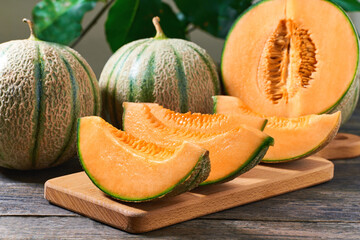 Wall Mural - sliced cantaloupe melon on wood plate and old wooden background.