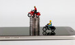 Smartphones and miniature people. Two miniature motorcycle riders and coins on the smartphone.
