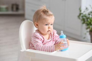 Sticker - Cute baby girl with bottle of water sitting on high chair in kitchen