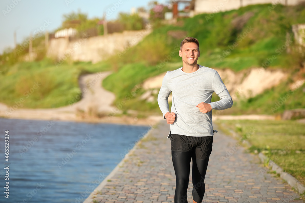 Sporty young man jogging near river